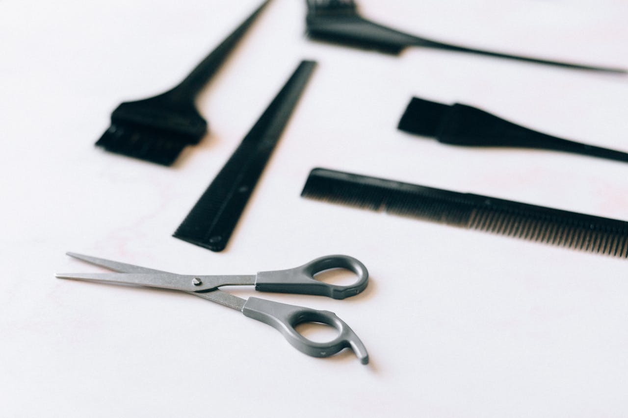 A collection of essential hairdressing tools including scissors and combs on a white surface.